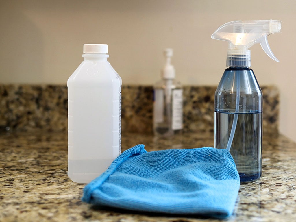Cleaning product with a sprayer and blue microfiber cloth sitting on the kitchen bench