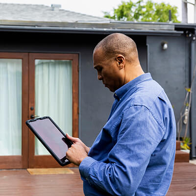 Male real estate agent using digital tablet while standing in front of house