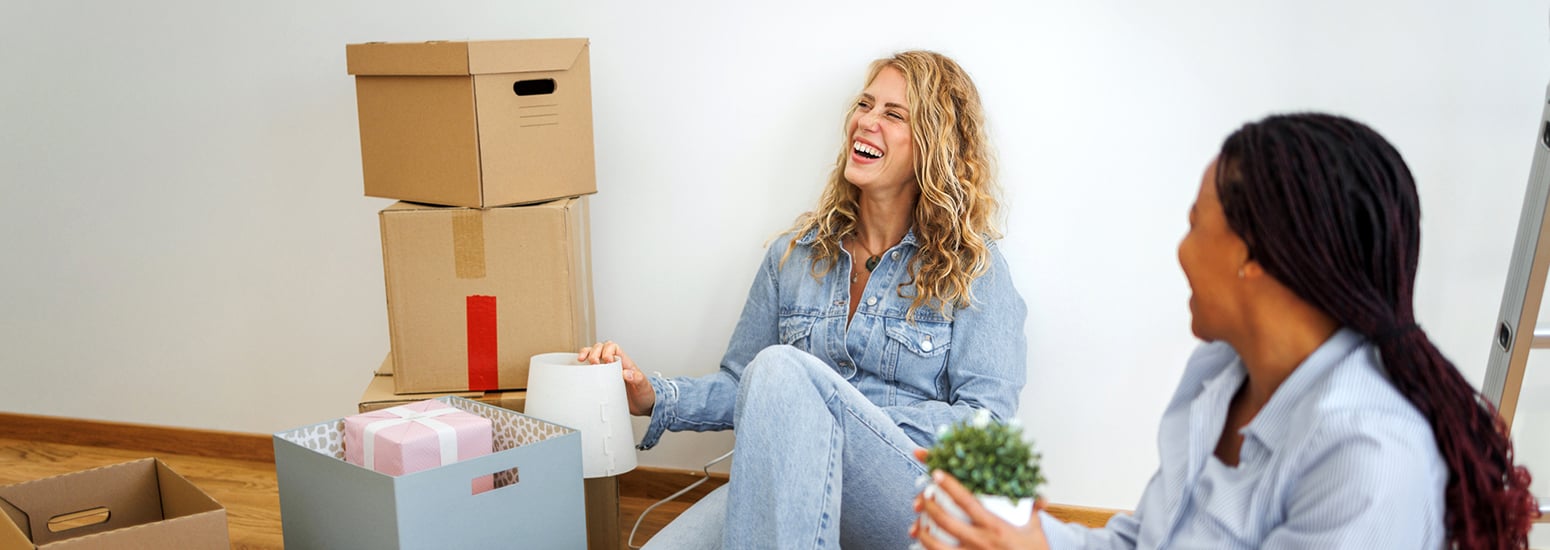 Two women sitting on floor next to cardboard boxes