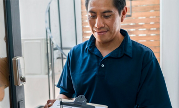 Man in blue shirt at front door with clipboard