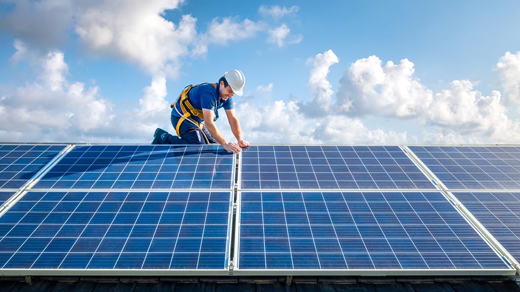 Technician installing solar panels on the roof of a house
