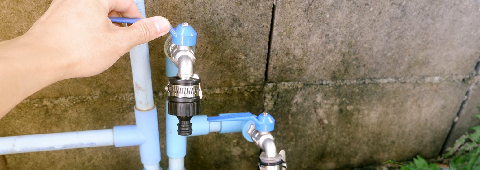 Hand turning off the mains water tap before going away.