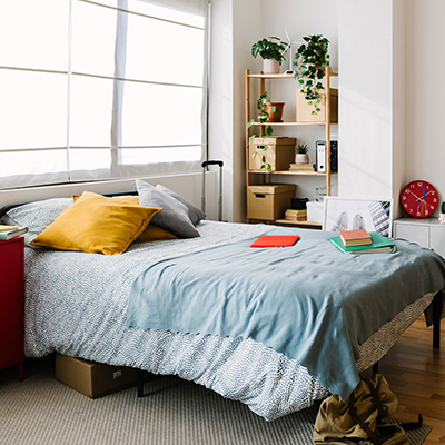 Interior of messy bedroom with bed and shelves