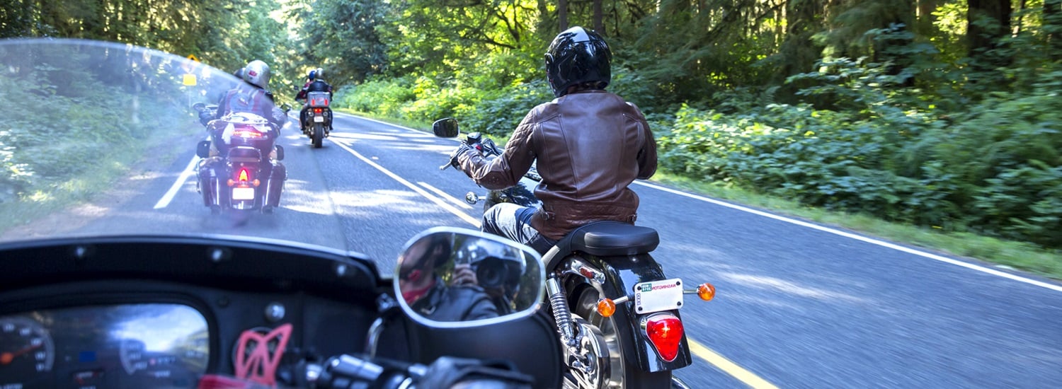 A group of motorcyclists riding through a scenic forest road - promoting comprehensive motorcycle insurance or motorbike insurance that covers group rides, touring, and rider safety in Australia.