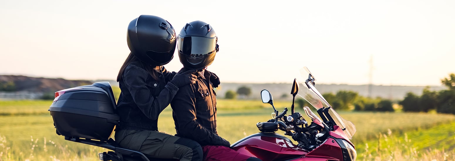 Couple seated on motorbike in countryside