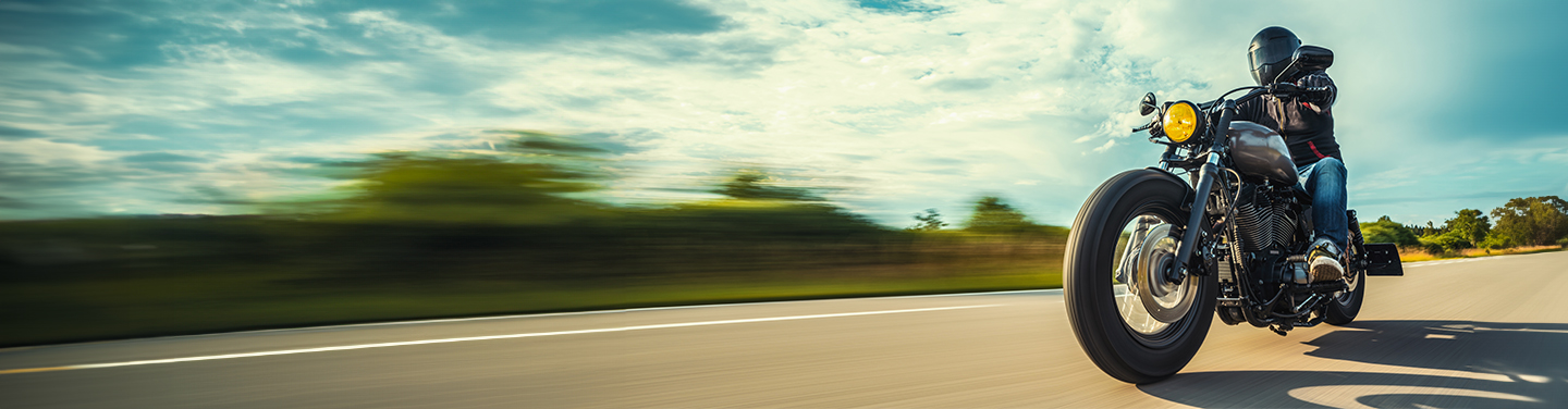Motorcyclist riding on an open road at sunset, wearing full protective gear - promoting comprehensive motorcycle insurance or affordable motorbike insurance in Australia.