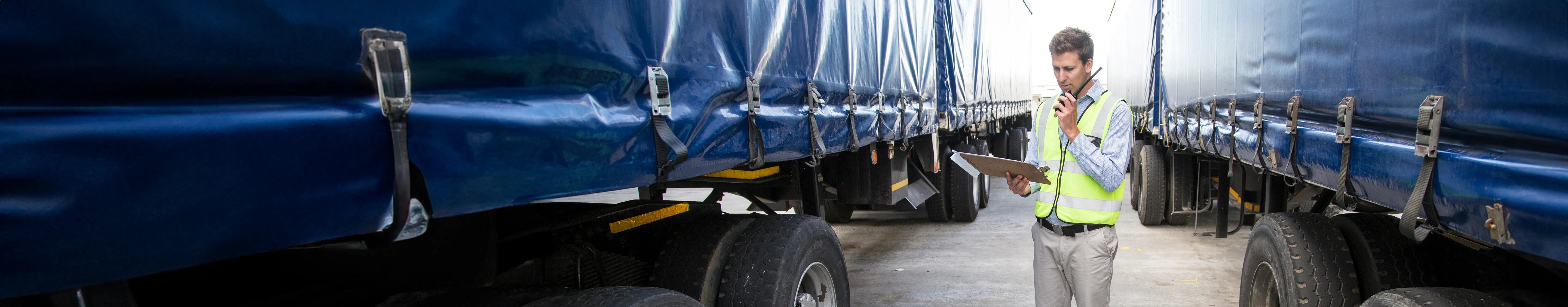 Carriers Load quote Info guide banner - Man talking into a radio standing between two trucks