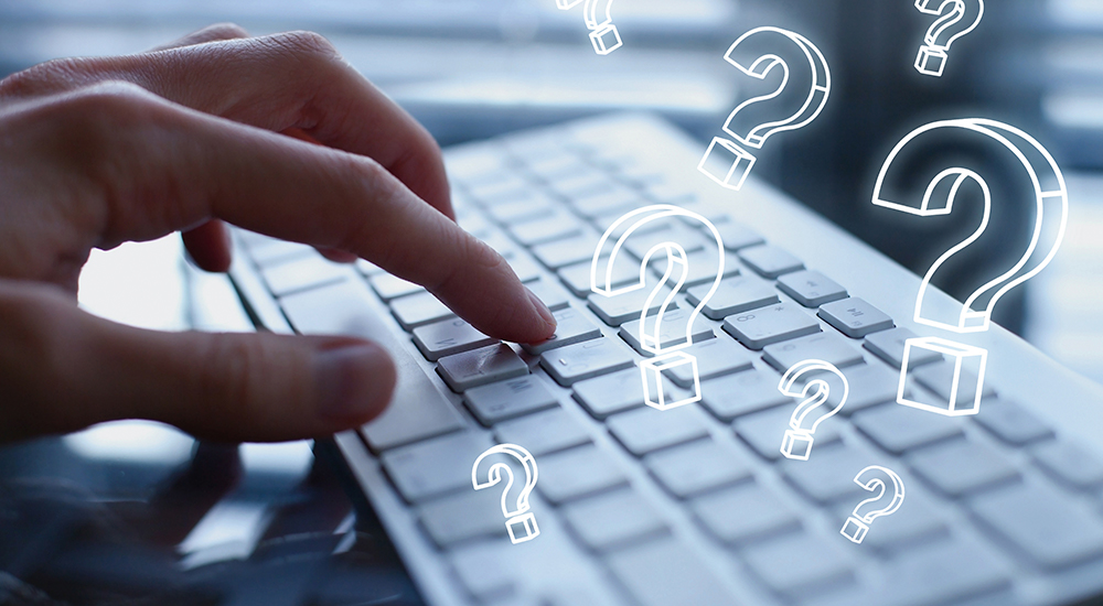 Graphical question marks float over fingers typing on keyboard