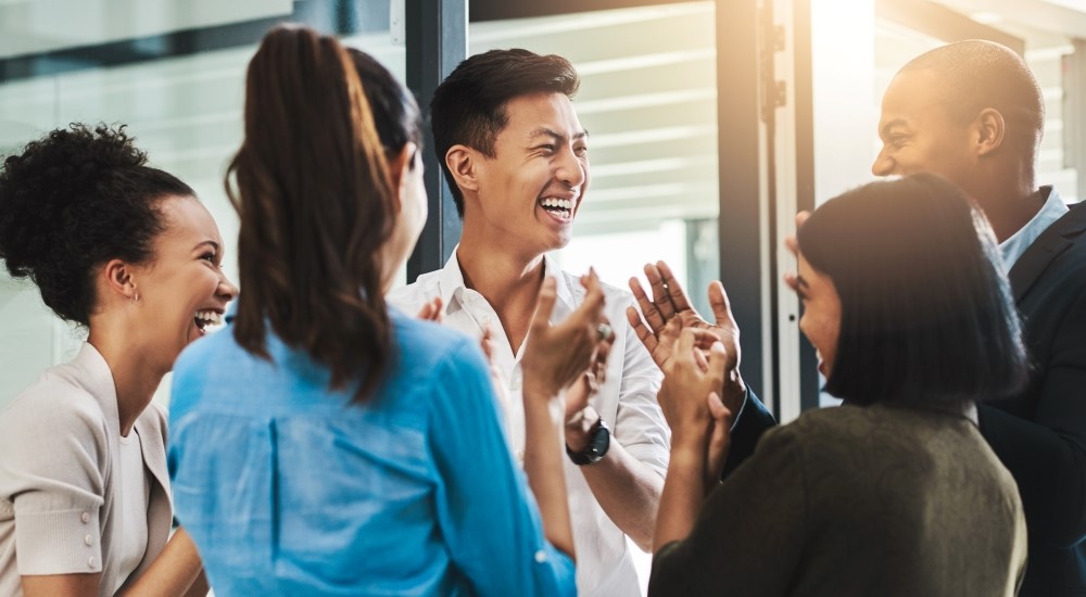 Group of colleagues applauding each other and laughing