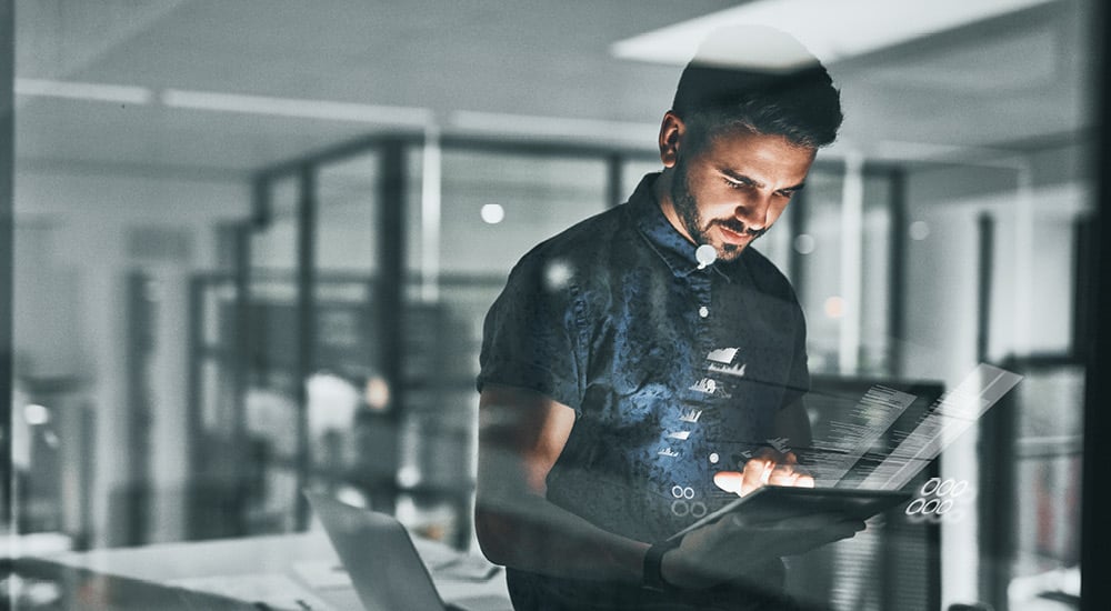 Young man in office looking at hand held tablet