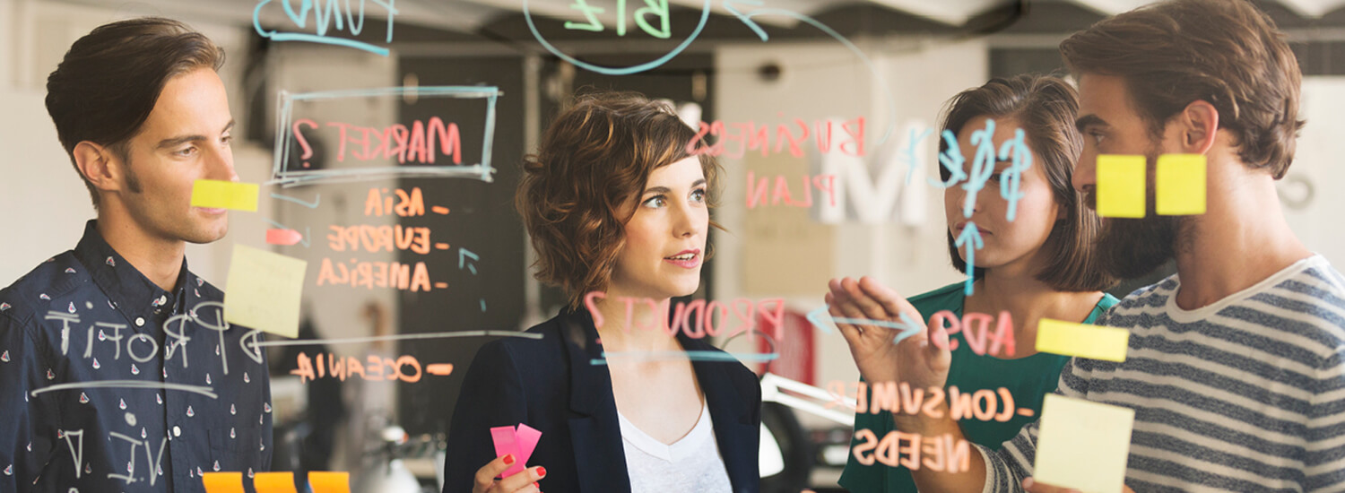 Business people discussing over plan on glass wall in office