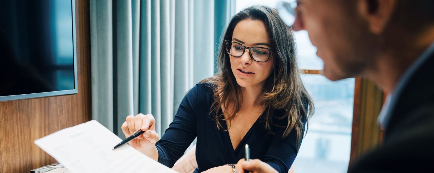 Male and female entrepreneur brainstorming over document during meeting in office.