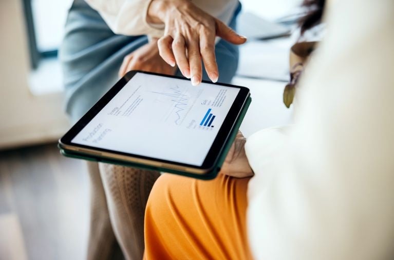 Close-up of two people looking at data on a tablet