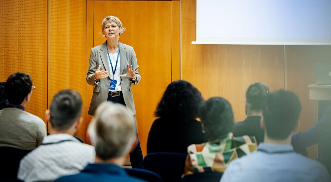 A presenter leading a professional training session or business workshop for a group of attendees in a meeting space