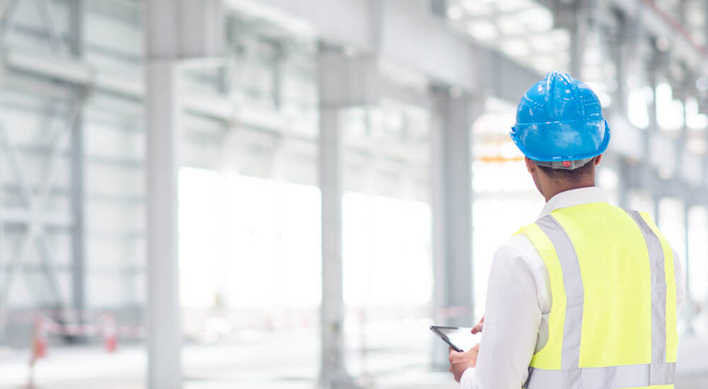 Engineer reviewing plans for construction site on digital tablet