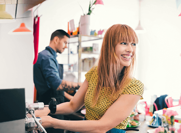 Young barista making coffee in her cafe