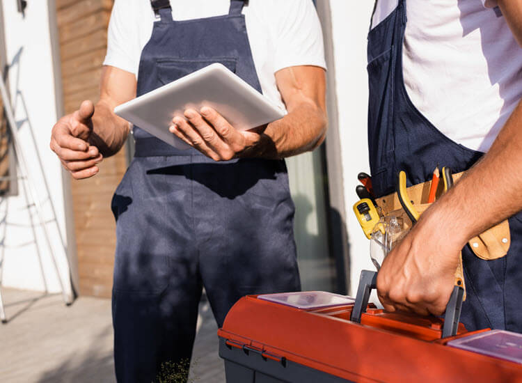 Tradie in discussion over a digital tablet near colleagues with toolbox