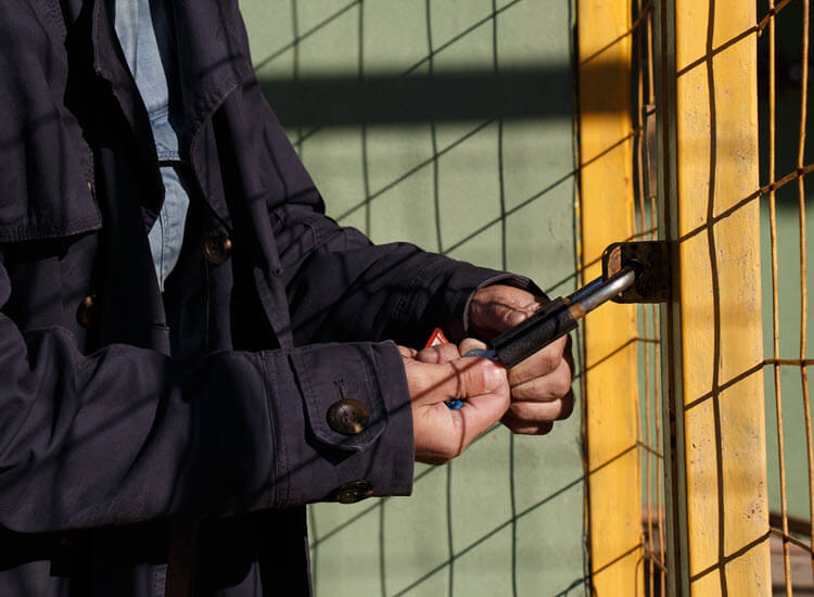 Man securing metal gates with padlock
