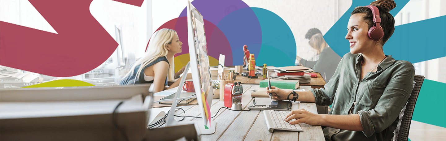 Modern open-plan office with people working at desks, featuring computers, notebooks, and colourful abstract wall graphics