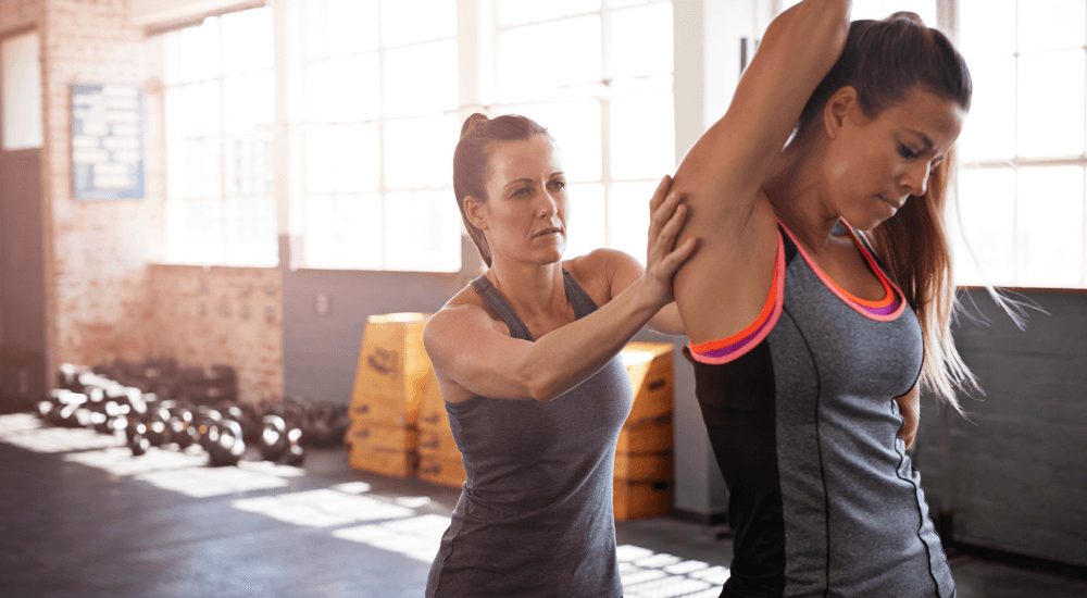 Active Recovery Clinic - two young women in a gym completing shoulder exercises