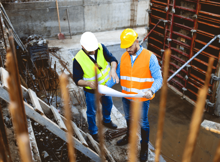 two men standing on site in hard hats and hi vis jackets