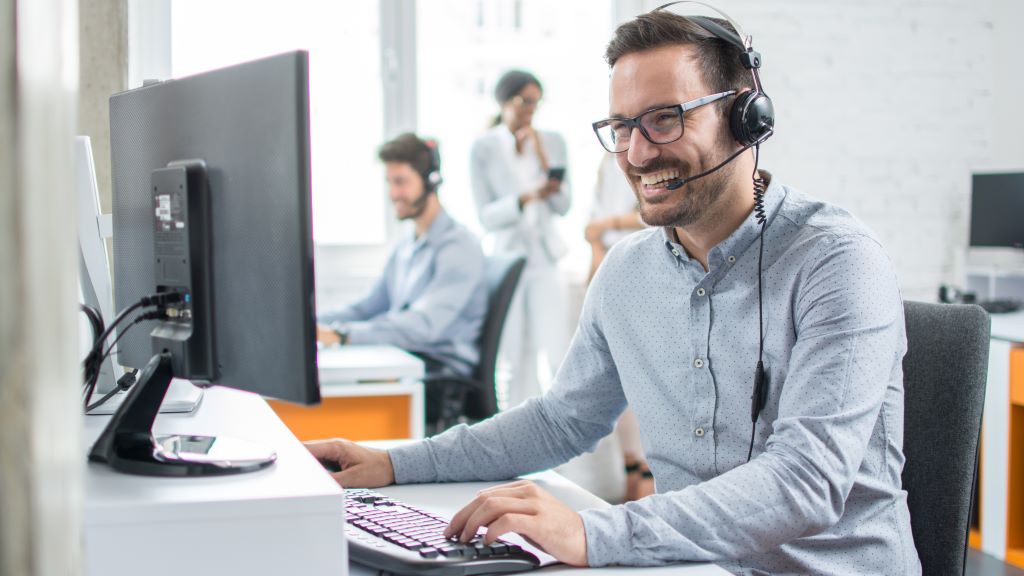 Male call centre worker smiling while talking to customer on the phone