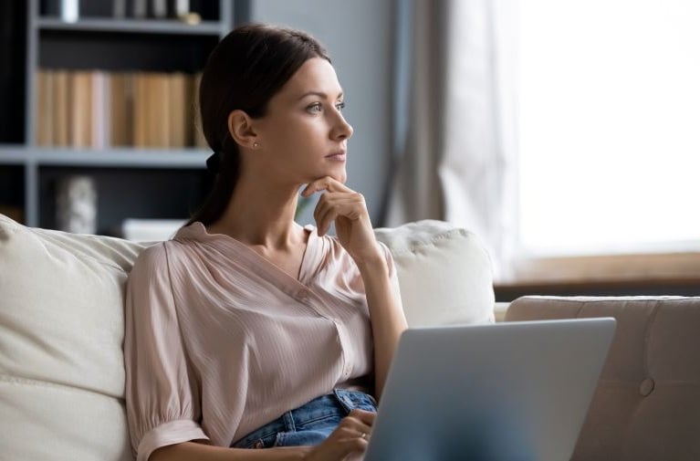 A woman using a laptop at home, representing the review of personal credit information and financial records.