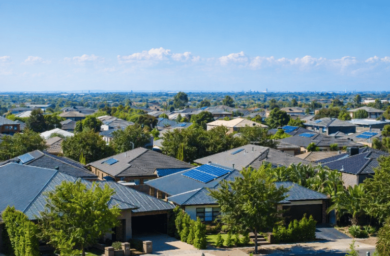 Aerial view of suburban homes with rooftop solar panels, representing clean energy housing.