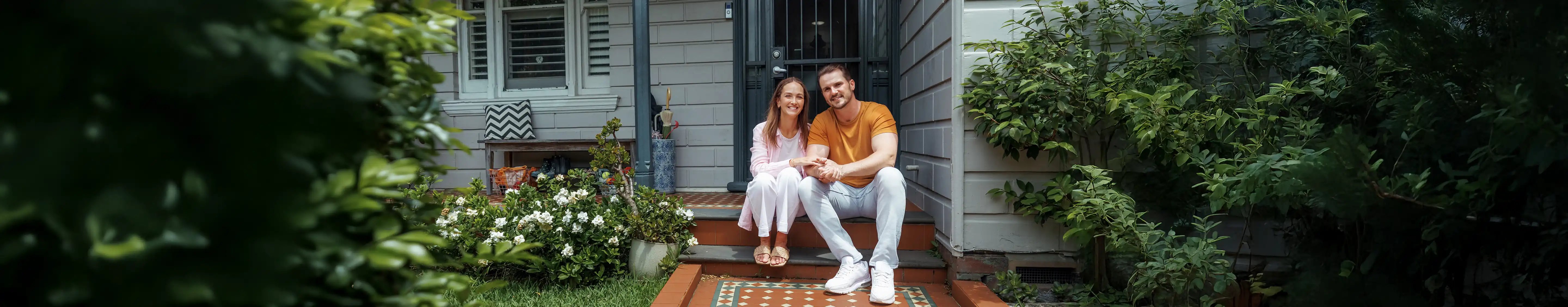 Young couple sitting on stairs of home - QBE LMI Insurance