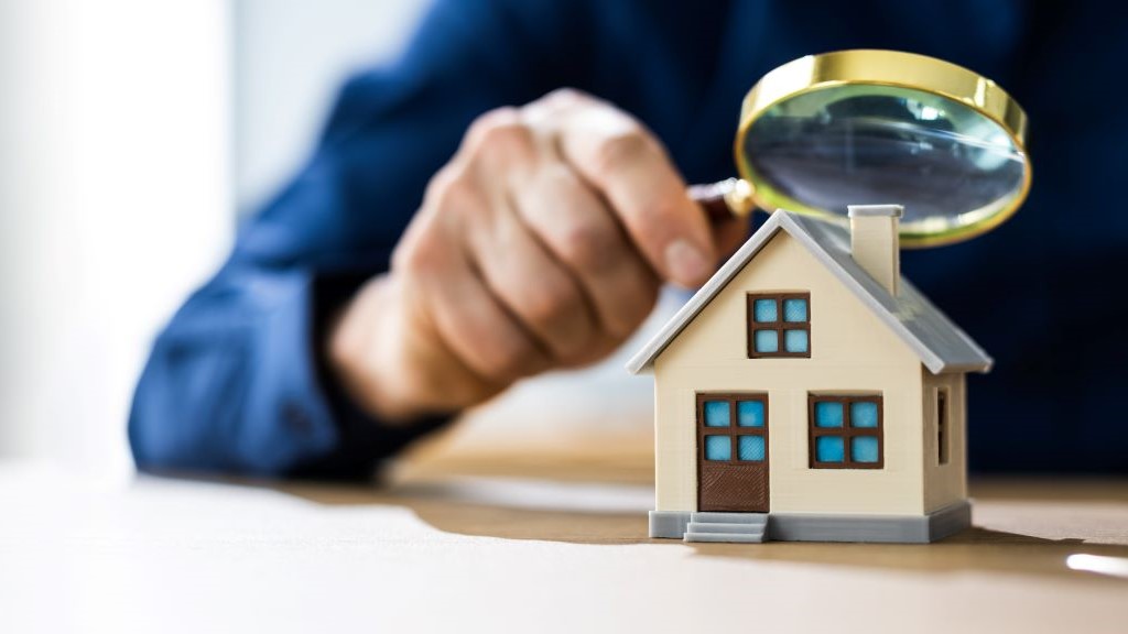 Close up of a man examining a model house with a magnifying glass