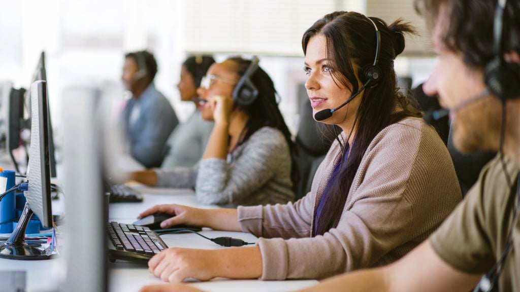 Call centre workers at their desktop computers wearing headsets