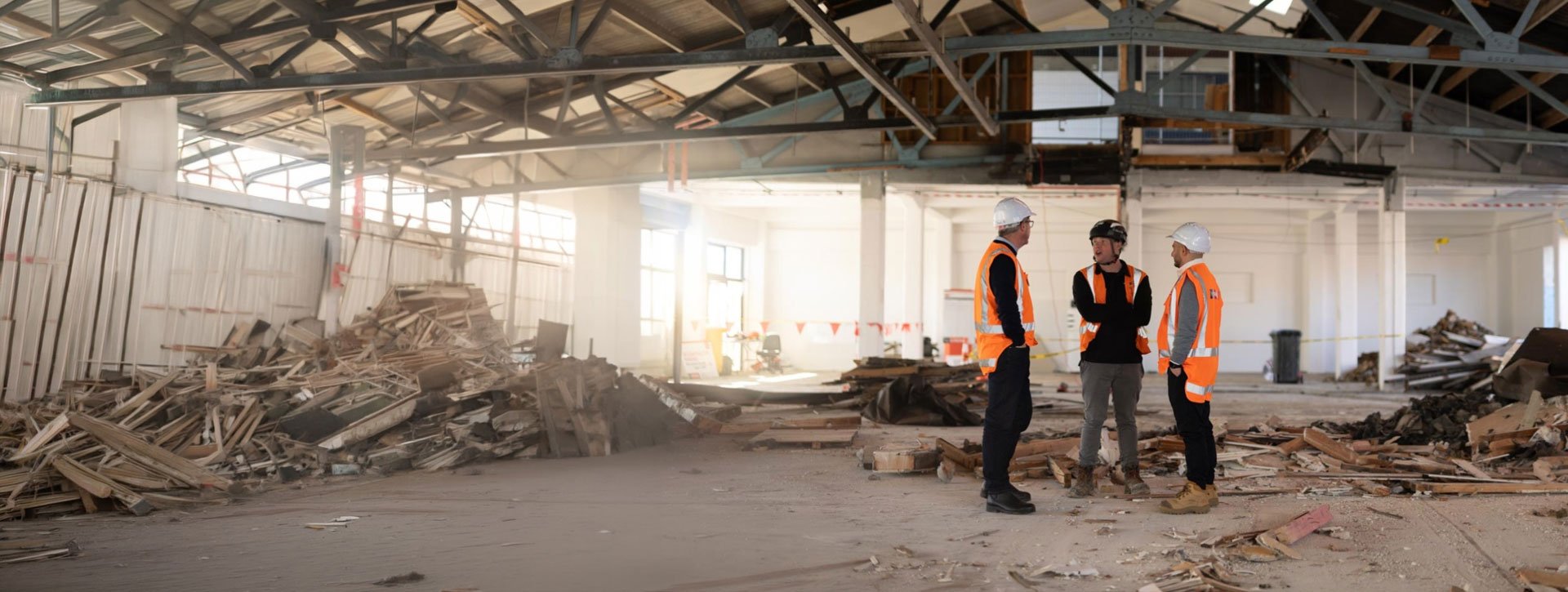 A group of construction workers wearing high‑visibility vests standing inside a partially stripped commercial building