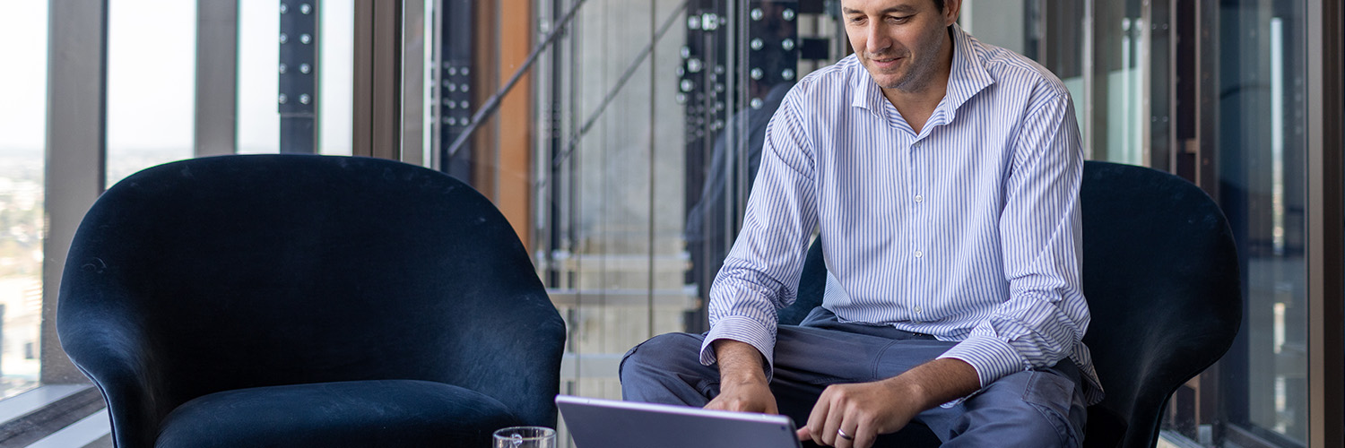 Man sitting on a chair, looking at his desktop