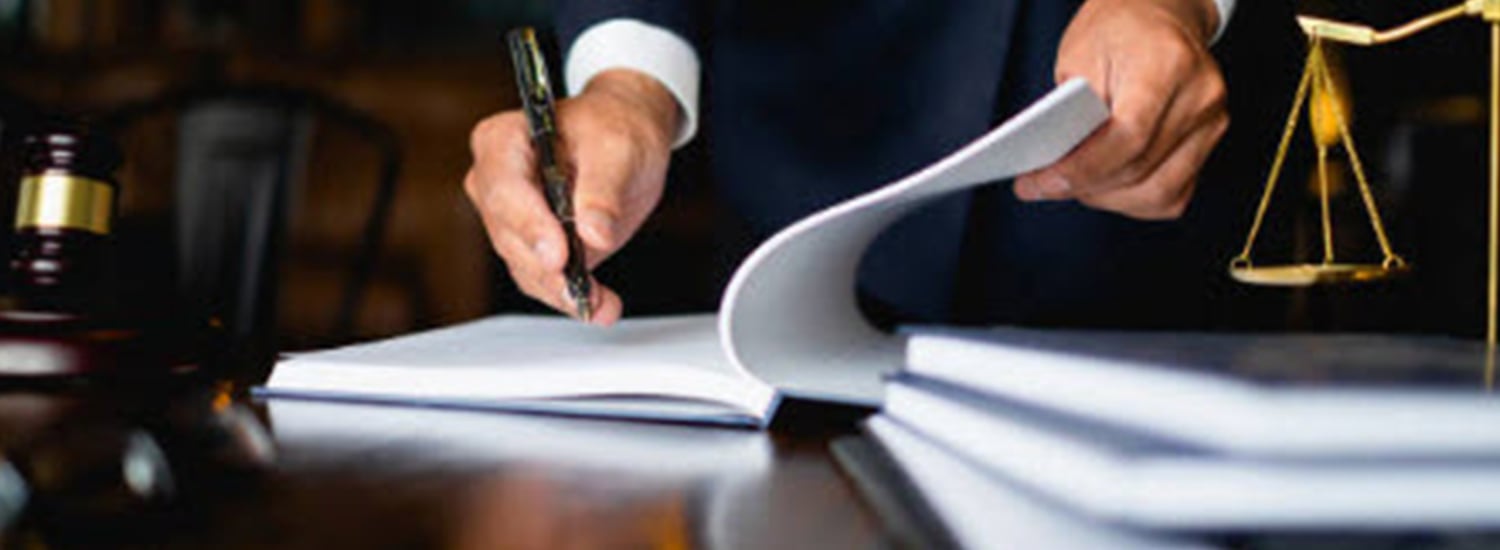man writing on a notepad on a desk